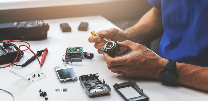 technician repairing broken digital camera lens in office